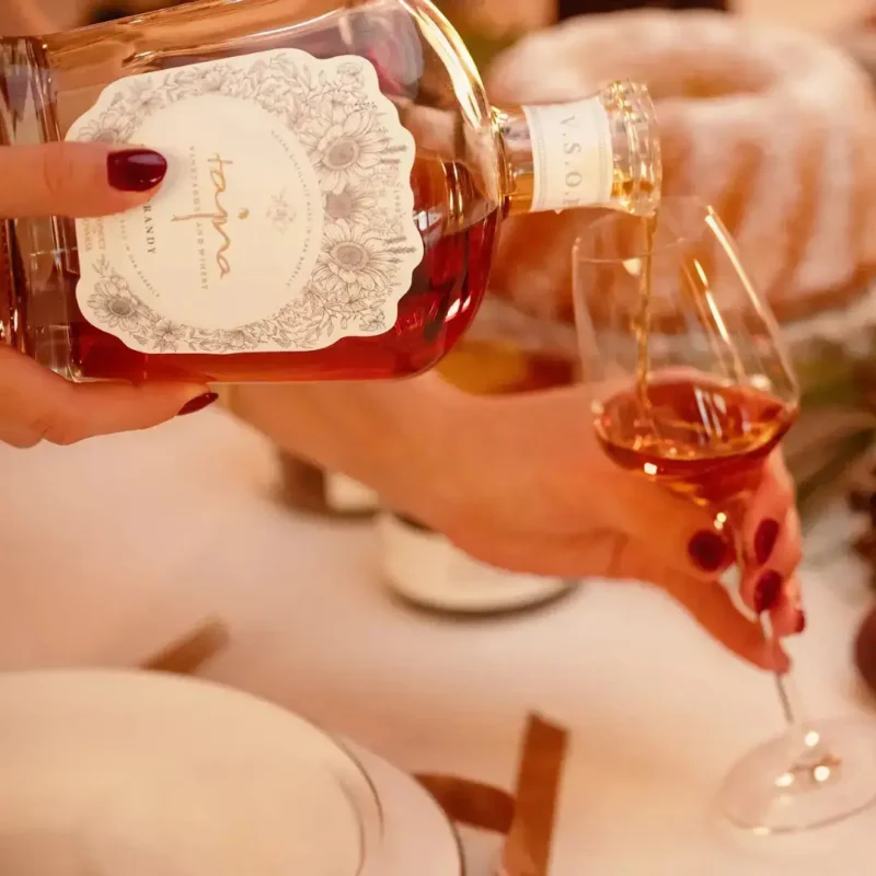ženská ruka nalieva do pohárika brandy Tajna